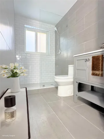 a bathroom with a double vanity sink a toilet a window and mirror