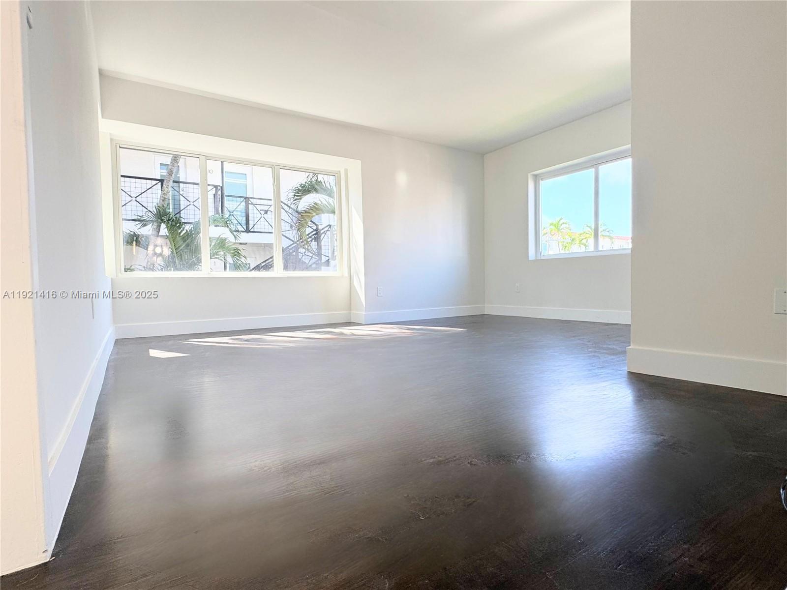 7325 Byron Avenue, Unit 8 Miami Beach, FL 33141 - Photo 9 of 16 an empty room with wooden floor and windows