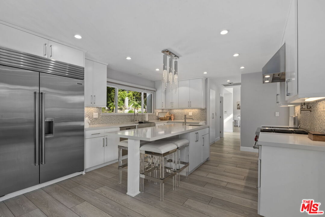 641 Walther Way Los Angeles, CA 90049 - Photo 12 of 53 a kitchen with stainless steel appliances granite countertop a kitchen island hardwood floor and a sink
