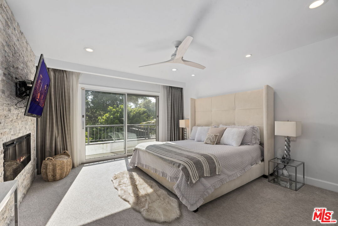 641 Walther Way Los Angeles, CA 90049 - Photo 23 of 53 a bedroom with a bed flat screen tv and a large window