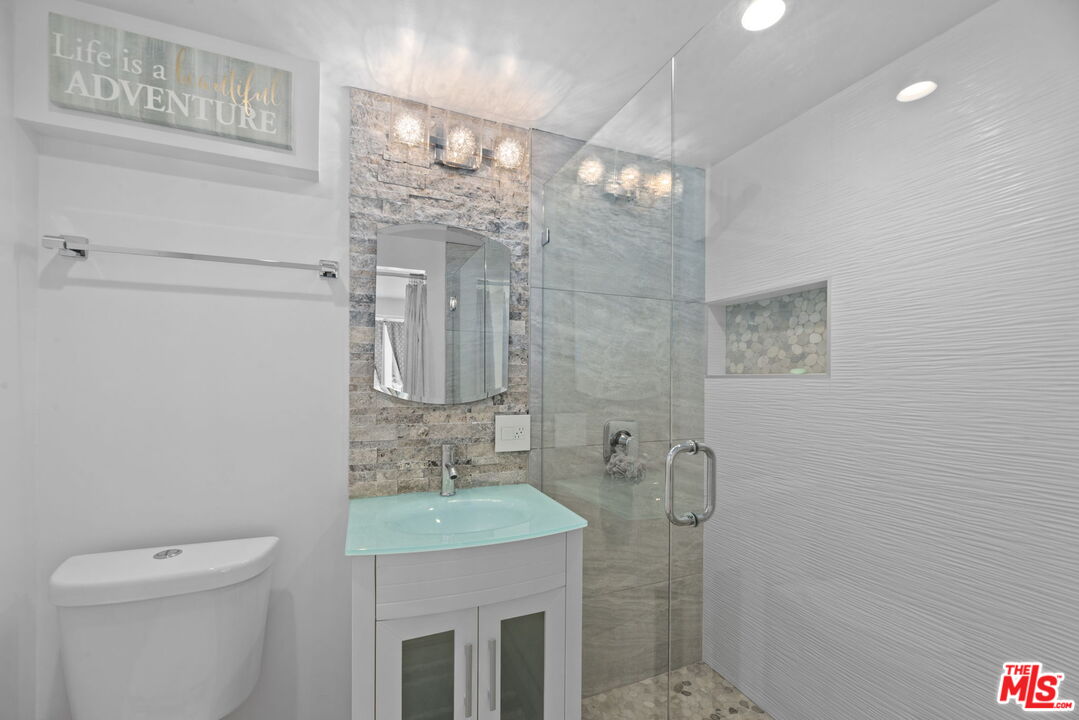 641 Walther Way Los Angeles, CA 90049 - Photo 35 of 53 a bathroom with a granite countertop sink a toilet and shower