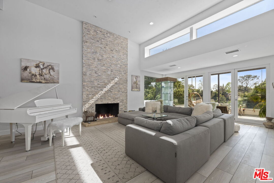 641 Walther Way Los Angeles, CA 90049 - Photo 6 of 53 a living room with furniture a fireplace and a floor to ceiling window