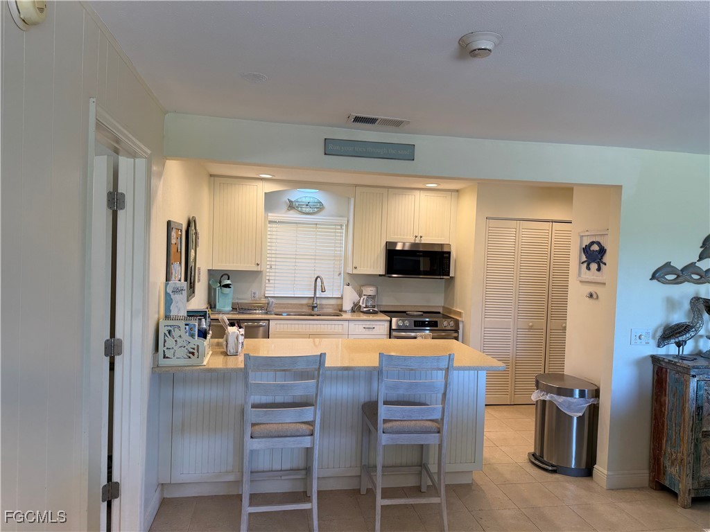 5117 Sea Bell Road, Unit G205 Sanibel, FL 33957 - Photo 9 of 31 a dining hall with stainless steel appliances a dining table and chairs with wooden floor
