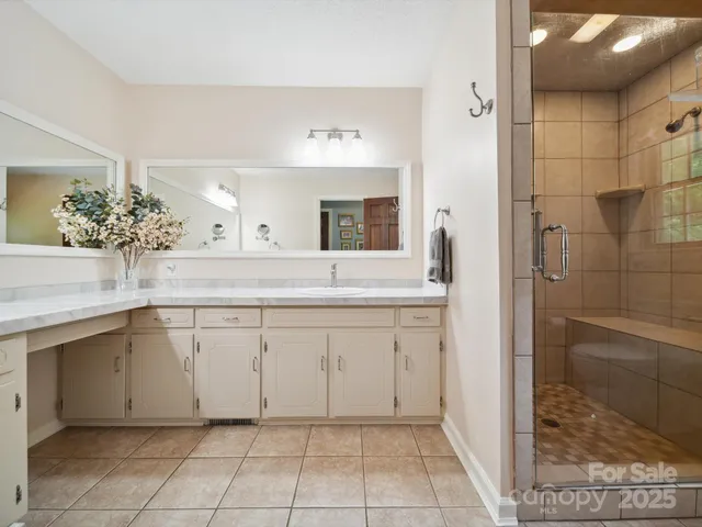 a spacious bathroom with a granite countertop sink a mirror and a shower