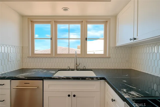 a kitchen with granite countertop a sink stove and cabinets