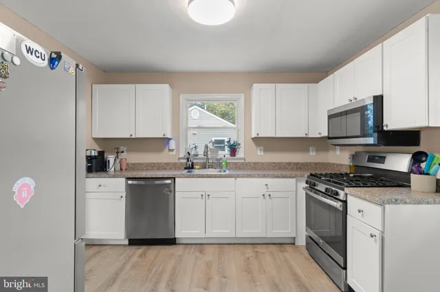 a kitchen with granite countertop a sink cabinets stainless steel appliances and a window