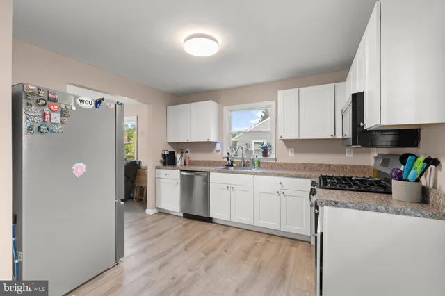 a kitchen with a refrigerator a stove top oven a sink a counter space and cabinets