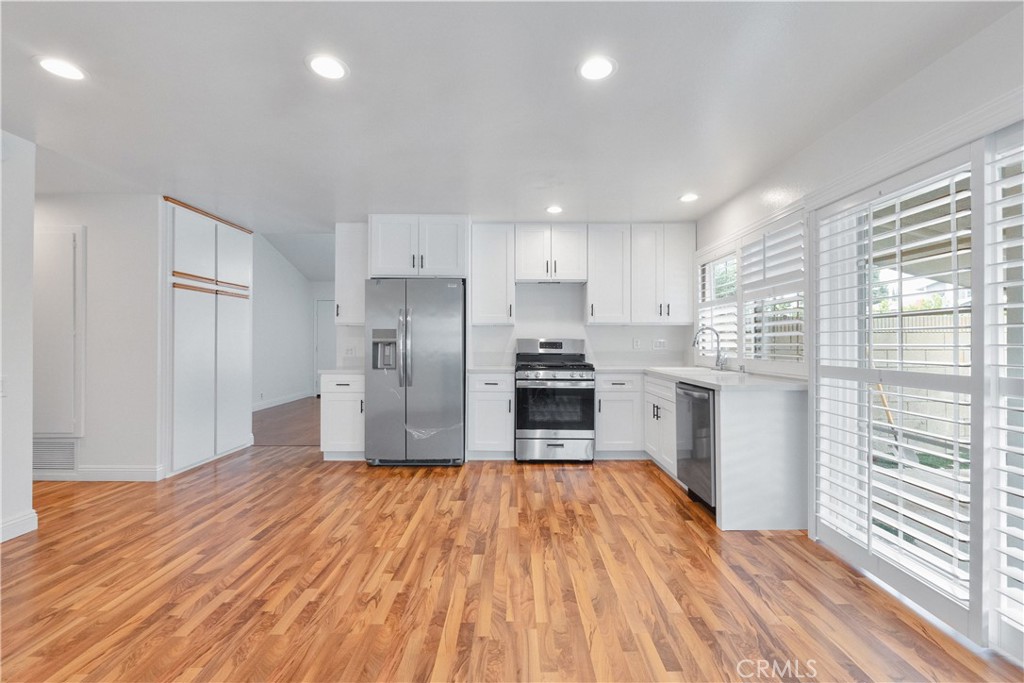 2172 Belhaven Avenue Simi Valley, CA 93063 - Photo 7 of 24 a kitchen with granite countertop a refrigerator oven a sink dishwasher and white cabinets with wooden floor