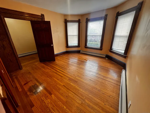 a view of an empty room with wooden floor and a window