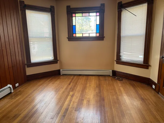 an empty room with wooden floor and windows