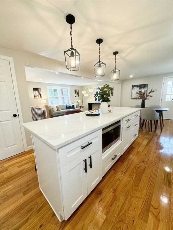 12 Evelyn Road Beverly, MA 01915 - Photo 8 of 37 a kitchen with stainless steel appliances a stove a sink and white cabinets with wooden floor