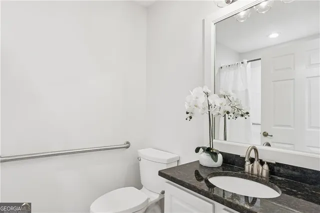 a bathroom with a granite countertop sink mirror vanity and toilet