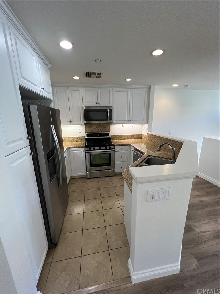 80 Hedge Bloom Irvine, CA 92618 - Photo 4 of 12 a open kitchen with stainless steel appliances granite countertop a refrigerator a sink a stove top oven and cabinets