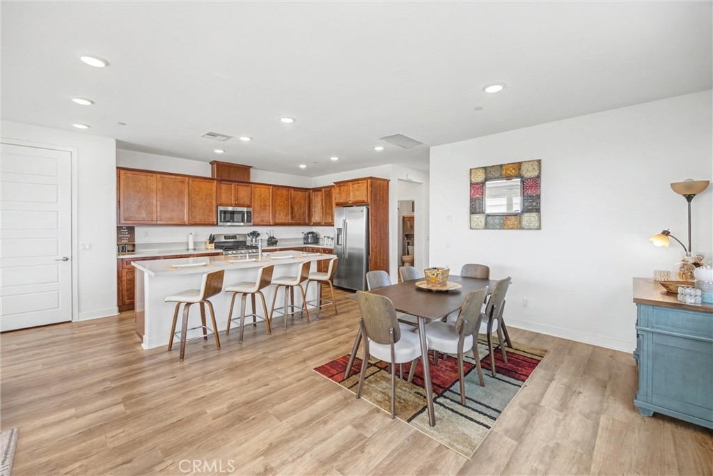1685 Spring Run Lane Beaumont, CA 92223 - Photo 19 of 57 a dining room with stainless steel appliances a dining table wooden floor and a kitchen view