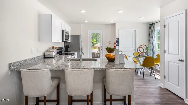 a dining room with stainless steel appliances granite countertop a table chairs and a refrigerator