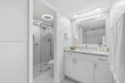 a bathroom with a double vanity sink toilet mirror and shower