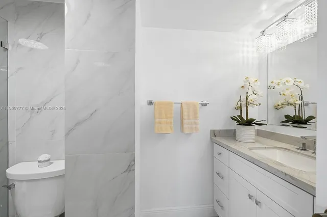 a bathroom with a granite countertop sink a toilet and mirror