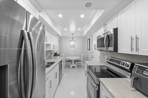 a kitchen with stainless steel appliances granite countertop a refrigerator a stove a sink a microwave oven with white cabinets and wooden floor