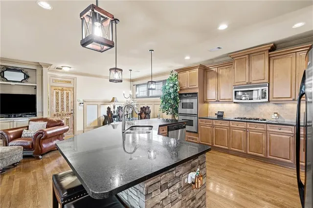 a kitchen with stainless steel appliances granite countertop a refrigerator a stove and a sink with granite countertops