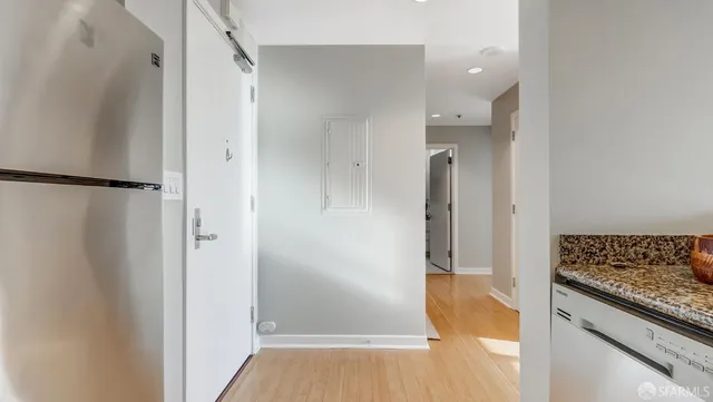 a view of a hallway with wooden floor and a bathroom