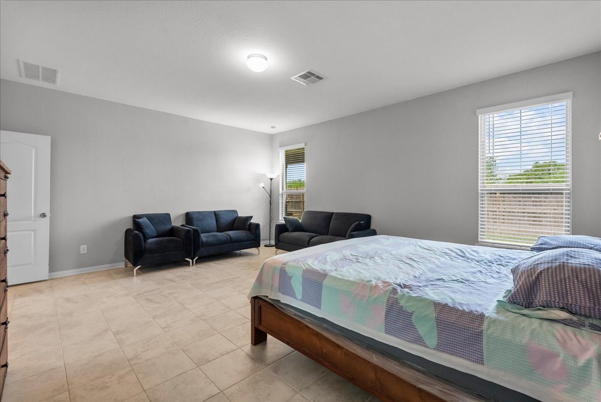 2320 Rosemary Street Rosenberg, TX 77469 - Photo 21 of 40 This spacious bedroom features a tiled floor, neutral walls, and ample natural light from two large windows.
