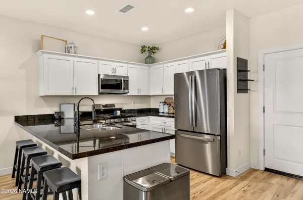 a kitchen with granite countertop a refrigerator a sink a stove a microwave and cabinets