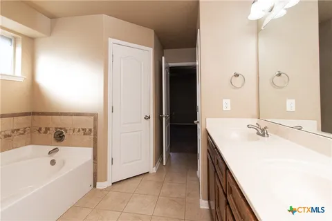 a spacious bathroom with a tub sink and mirror