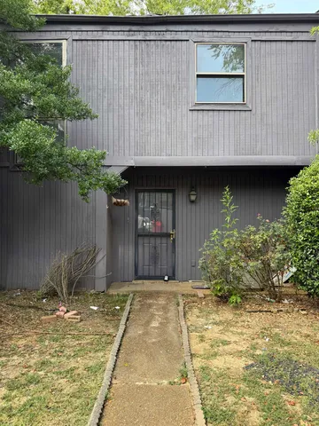 a view of a house with a small yard plants and large tree