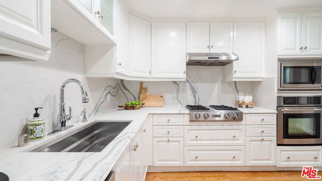 a kitchen with granite countertop white cabinets and stainless steel appliances