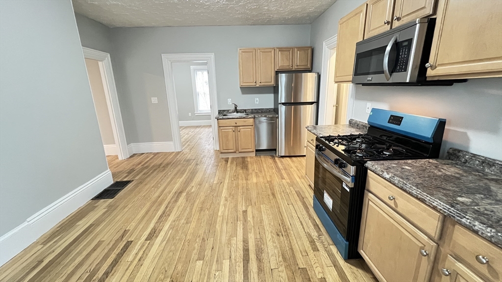 a kitchen with granite countertop a stove a sink dishwasher and a refrigerator