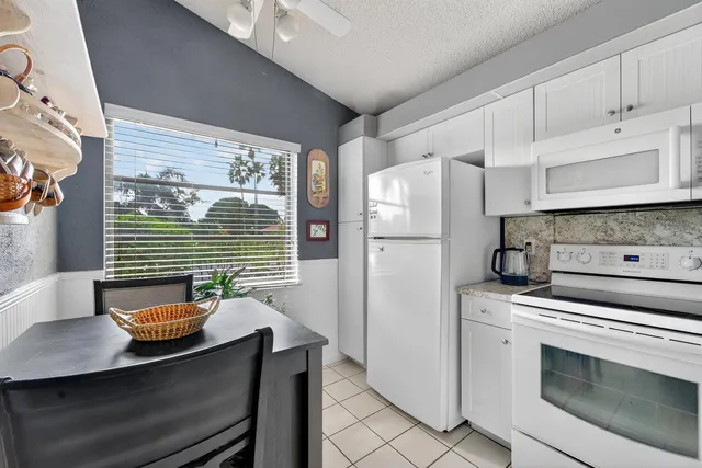 a kitchen with stainless steel appliances a stove a refrigerator a sink and white cabinets