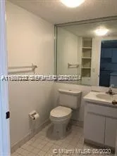 a bathroom with a granite countertop toilet a sink and mirror