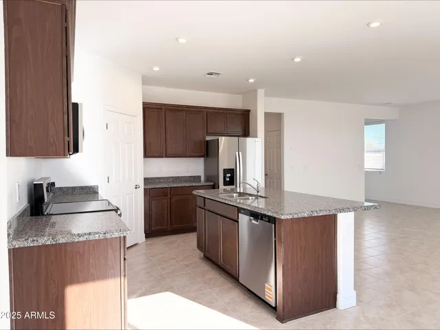 a kitchen with stainless steel appliances granite countertop a stove top oven a sink and a refrigerator