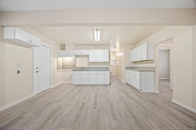 a kitchen with white cabinets and wooden floor