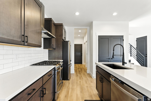 6039 North Westridge Road Heber City, UT 84032 - Photo 6 of 22 Modern kitchen featuring rich cabinetry, white subway tile backsplash, light countertops, stainless steel appliances, and wood-finish flooring