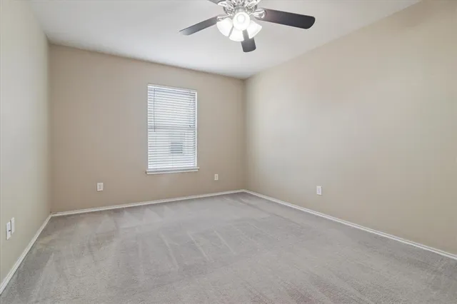 an empty room with a chandelier fan and windows