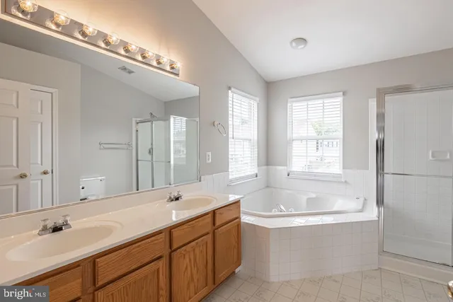 a spacious bathroom with a tub double sink and mirror