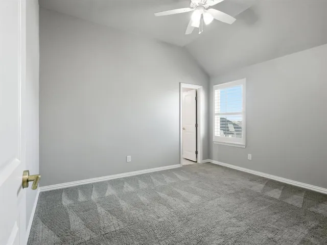 an empty room with chandelier fan and windows