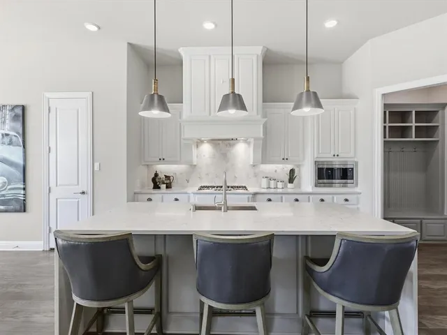 a kitchen with stainless steel appliances kitchen island granite countertop a dining table chairs and a refrigerator