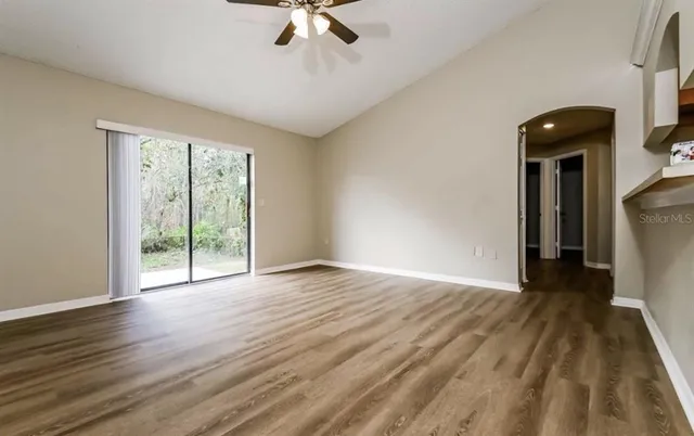 a view of an empty room with wooden floor and a window