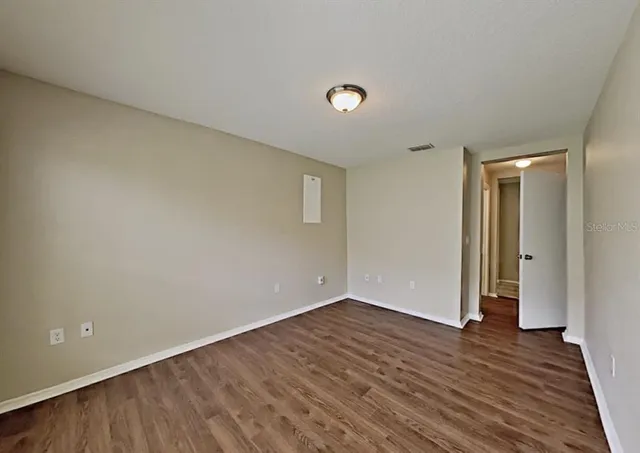 a view of an empty room with wooden floor and closet