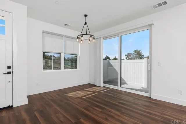an empty room with wooden floor closet and windows