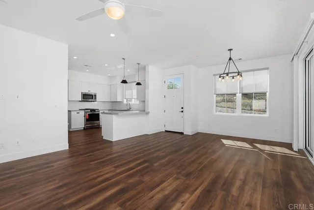 a view of kitchen and empty room with wooden floor
