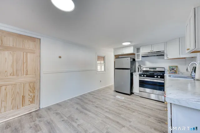 a large white kitchen with sink and cabinets