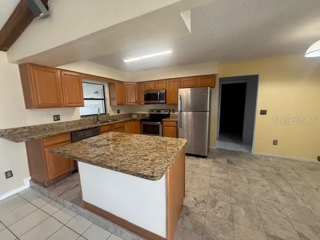 a kitchen with stainless steel appliances granite countertop a stove top oven a sink and a refrigerator