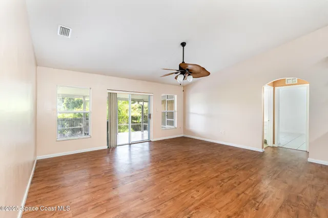 a view of an empty room with window and wooden floor