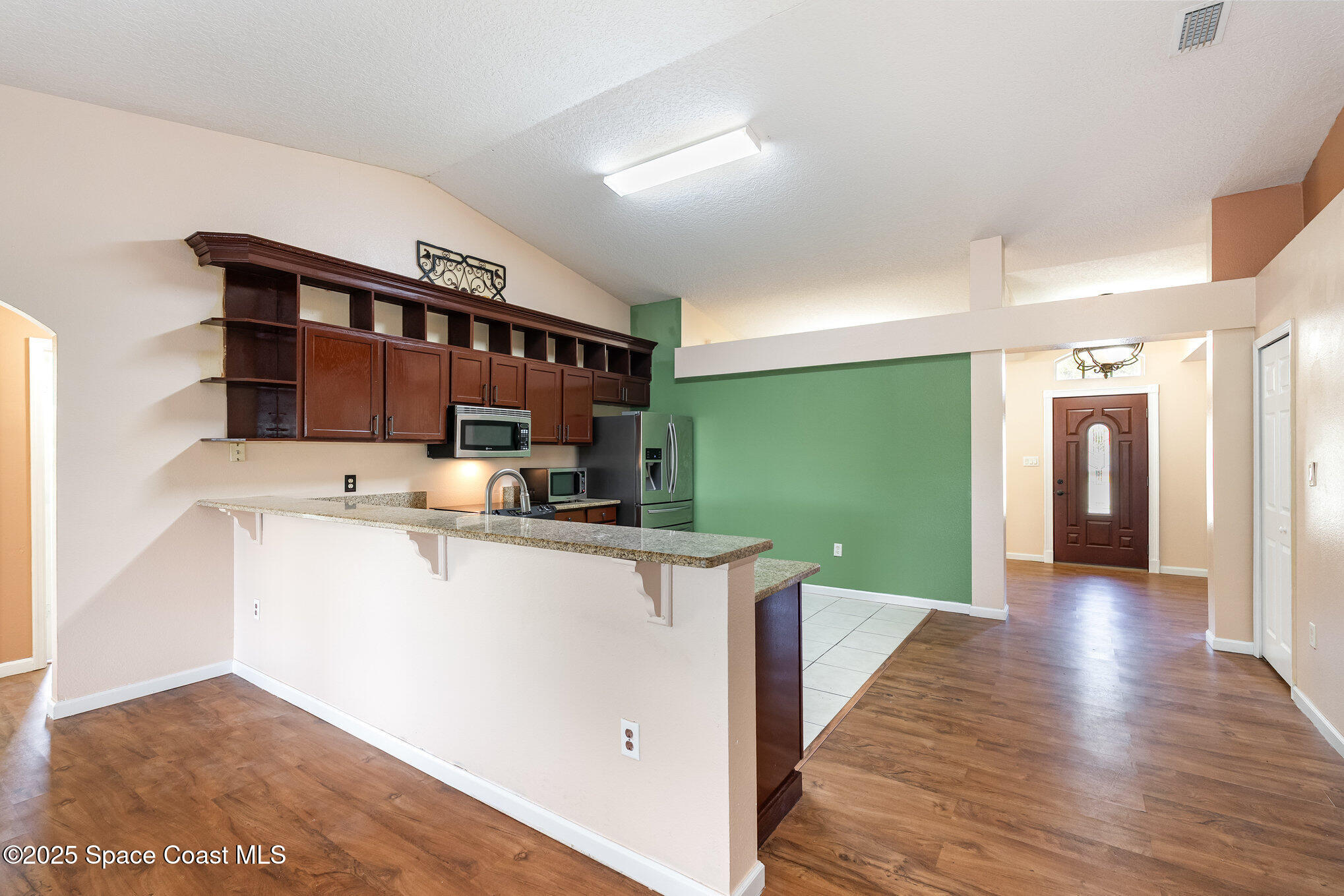6105 Banyan Street Cocoa, FL 32927 - Photo 10 of 27 a view of a kitchen with kitchen island a sink wooden floor and a living room view