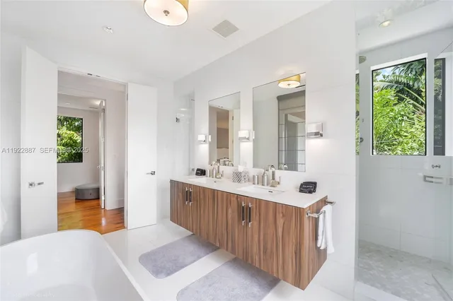 a large bathroom with a double vanity sink a large mirror and a bathtub