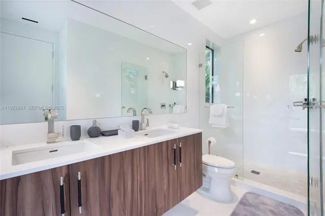 a bathroom with a sink toilet double vanity and shower