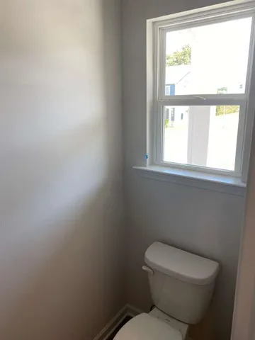 a white toilet sitting in a bathroom next to a window
